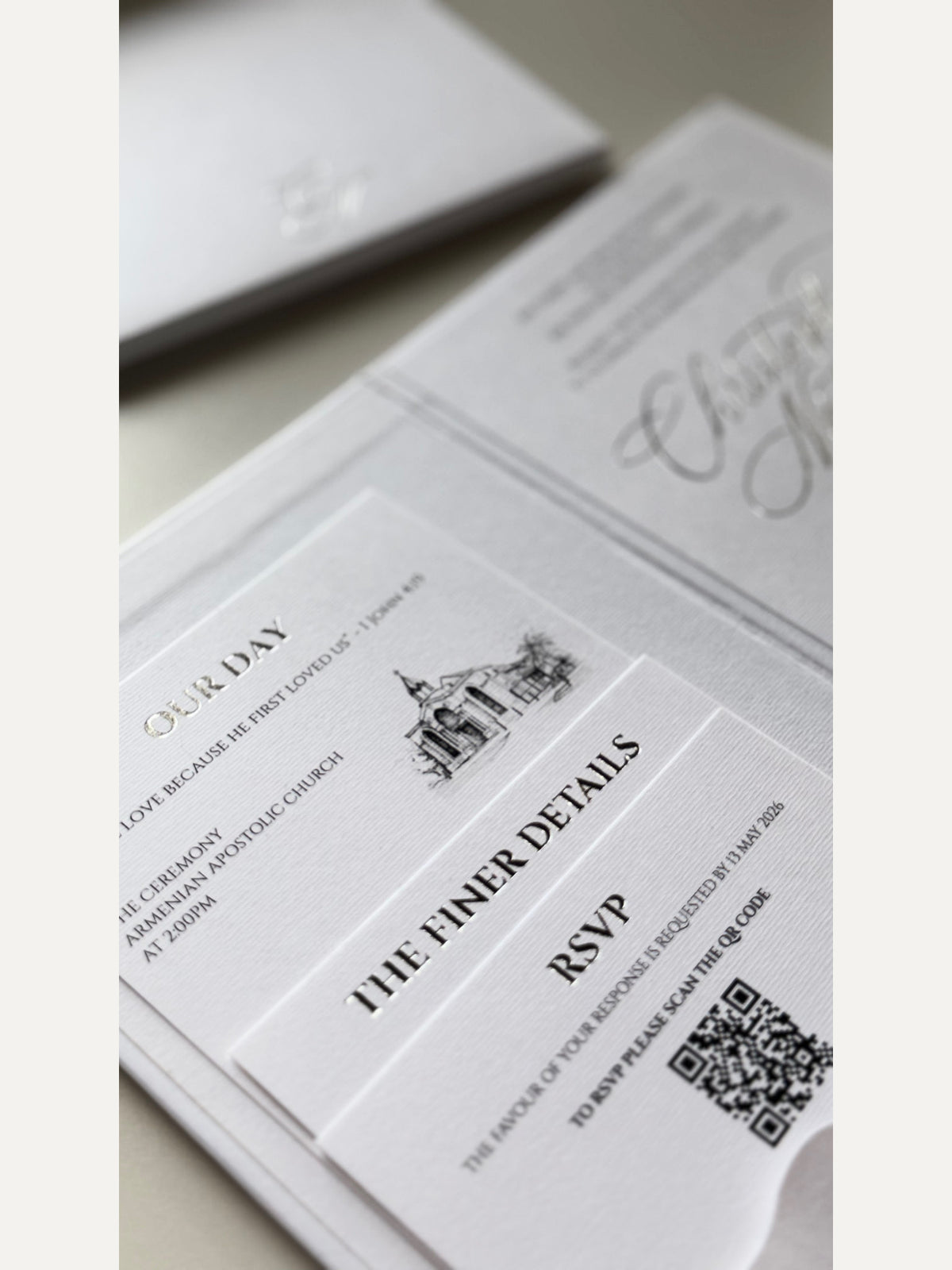 Close-up of an invitation booklet pocket holding a venue illustration details card and an RSVP card with QR code.
